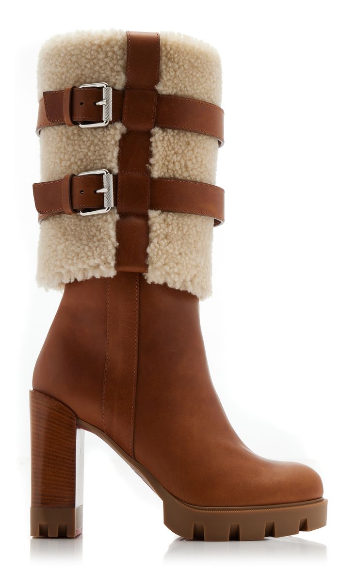 a pair of women's brown leather high heel boots with shearling lining and buckle details are shown. the boots have a chunky platform heel and a slightly squared toe. they appear to be made of highquality leather and are designed for both style and warmth.