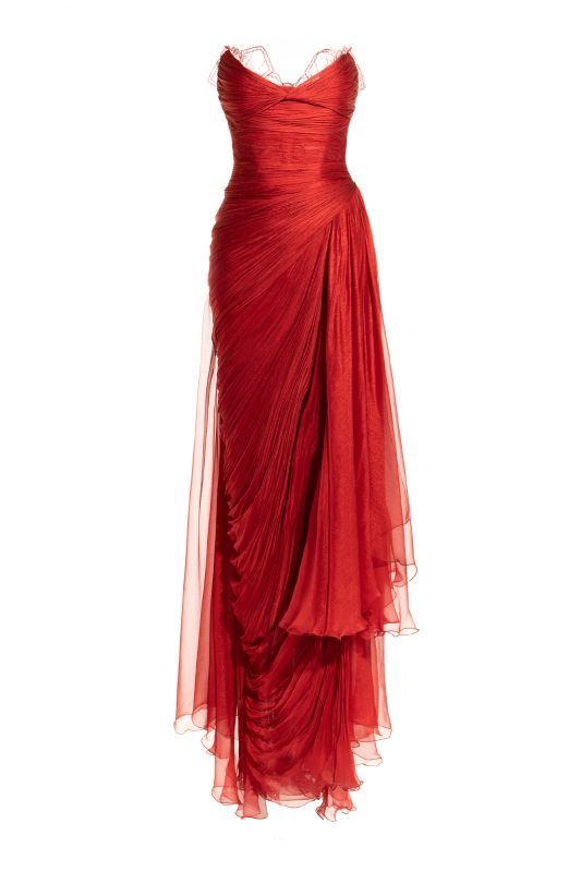 a red chiffon formal evening gown. the dress is sleeveless, features lace trimming along the sweetheart neckline and has a draped design with a gathered bodice and a flowing skirt. the dress is floorlength.