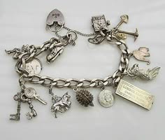 a silver charm bracelet with many different charms. the charms include a heart lock, a shoe, a bird, a horse, a flower, an insect, a key, and a tag that says "london, england."