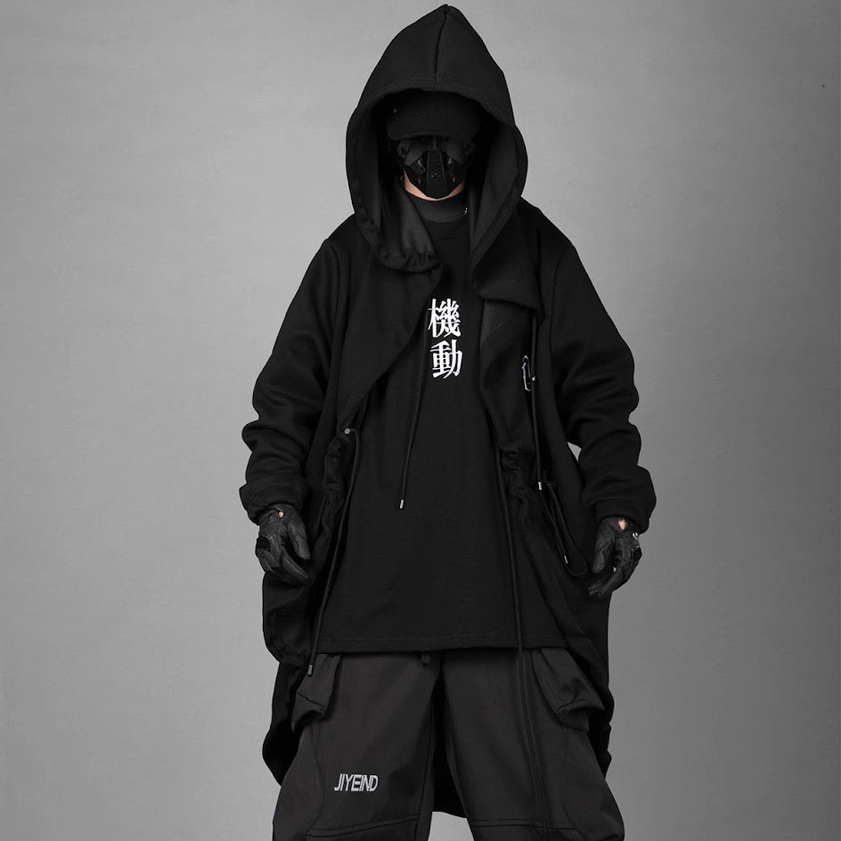 a man wearing a black hoodie with japanese characters, black pants, and a black mask. he is standing in front of a gray background. the model is looking down and his face is obscured by the mask. he is wearing a black hoodie with a large hood and a black mask that covers his entire face. the hoodie has a zipper in the front and two pockets on the sides. the model is also wearing black pants. he is standing in front of a gray background.