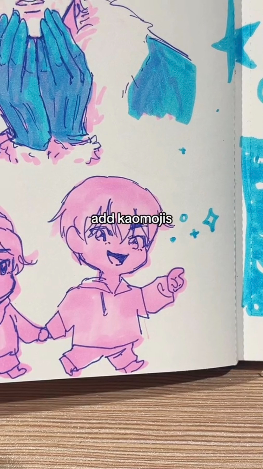 a drawing of a cute cartoon boy and girl holding hands and smiling. they are both pink and walking together.  the girl is on the left side, and the boy is on the right. the boy has short hair and the girl has long hair with pigtails. they are both wearing simple outfits. there is a large blue star in the top right corner and some small stars scattered around.  the words "add kaomojis" are written in black marker above the boy.