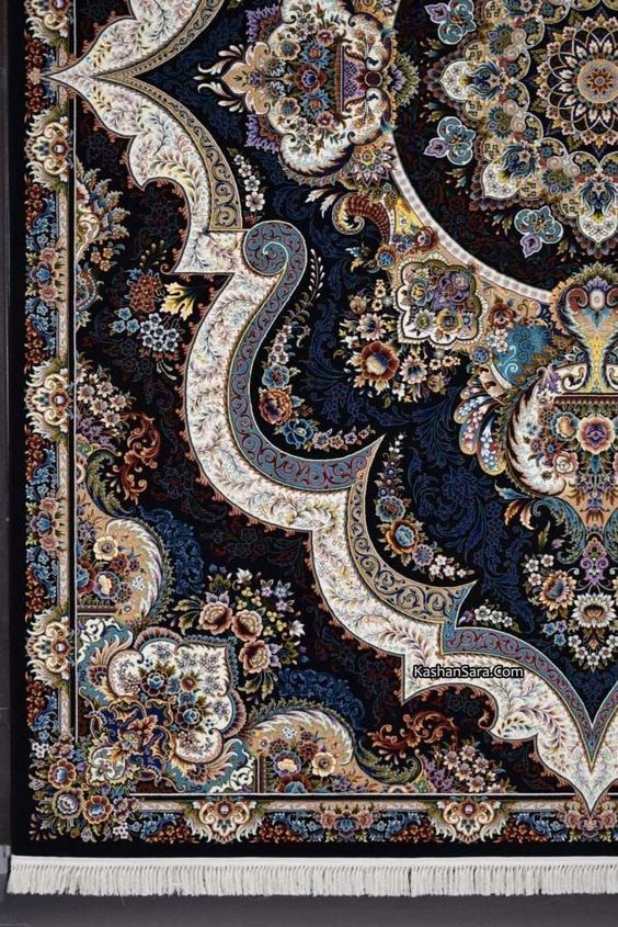 a closeup view of a detailed persian carpet with a floral pattern. the carpet features a dark background and intricate designs in beige, blue, and brown. the pattern includes curving lines and flower motifs, and the carpet has a fringe at the bottom. the website kashansara.com is faintly visible in the middle.
