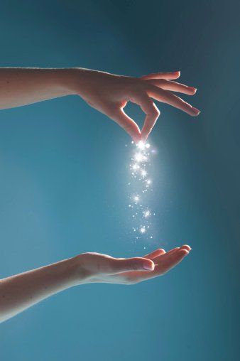 a hand is dropping glitter into another hand on a blue background.