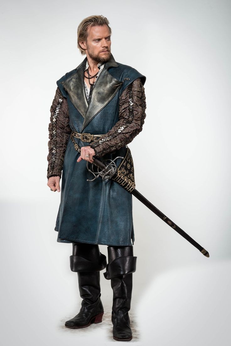a fullbody studio shot of a man dressed in a renaissancestyle costume. he is wearing a tealcolored long coat with textured sleeves, a belt with a decorative buckle, high black leather boots, and a sword. he appears to be in character, with a serious expression on his face.  the background is plain white.