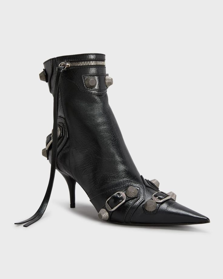 a black leather boot with a stiletto heel is shown. the boot has a pointed toe, zipper at the top, buckle details, and studs.