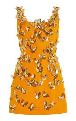an orange sleeveless mini cocktail dress adorned with gold butterfly embellishments is shown on a white background. the dress has a round neckline and the embellishments are scattered across the entirety of the dress.