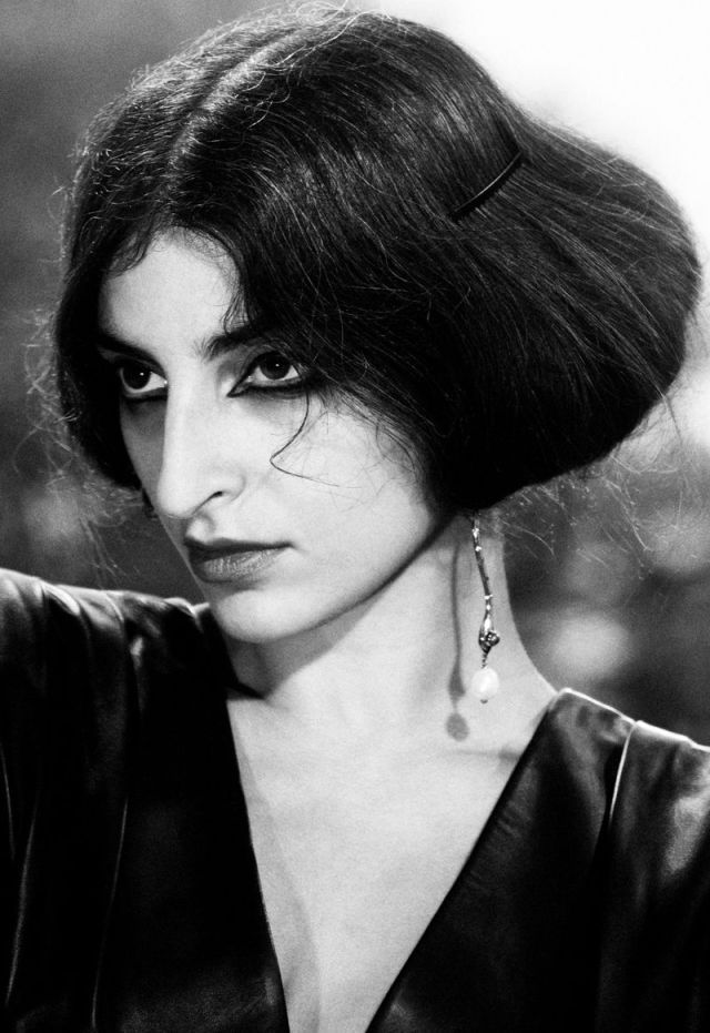 a black and white portrait of a woman with dark hair and eyes, wearing a black leather jacket. she is looking directly at the camera. the image has a classic, vintage feel.