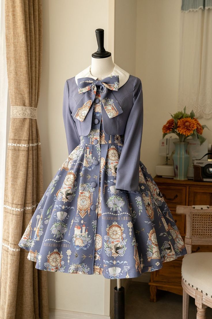a blue lolita fashion dress with a clock and teacup print is displayed on a mannequin. the dress has a matching cropped jacket.