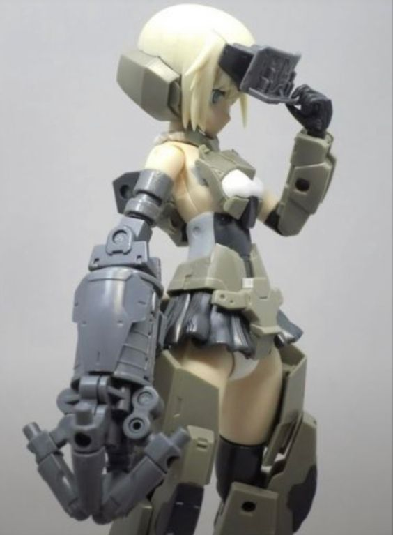 the image shows a detailed figurine of a female character in a futuristic, militaristic outfit. she is posed with her left hand raised to her forehead, as if shielding her eyes from the sun or looking at something in the distance. her outfit features a mix of white, gray, and black armor plating, with exposed areas revealing a black and white leotardlike garment underneath. her hair is blonde and styled in a short bob. the figurine's left arm is particularly detailed, with multiple joints and what appears to be a weapon or tool attached to the hand.