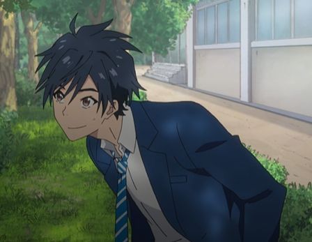 an anime boy with green hair and blue eyes wearing a blue school uniform with a blue and white striped tie is leaning forward slightly and smiling. he's outside a school building with green trees and grass around him. the lighting is bright and sunny.