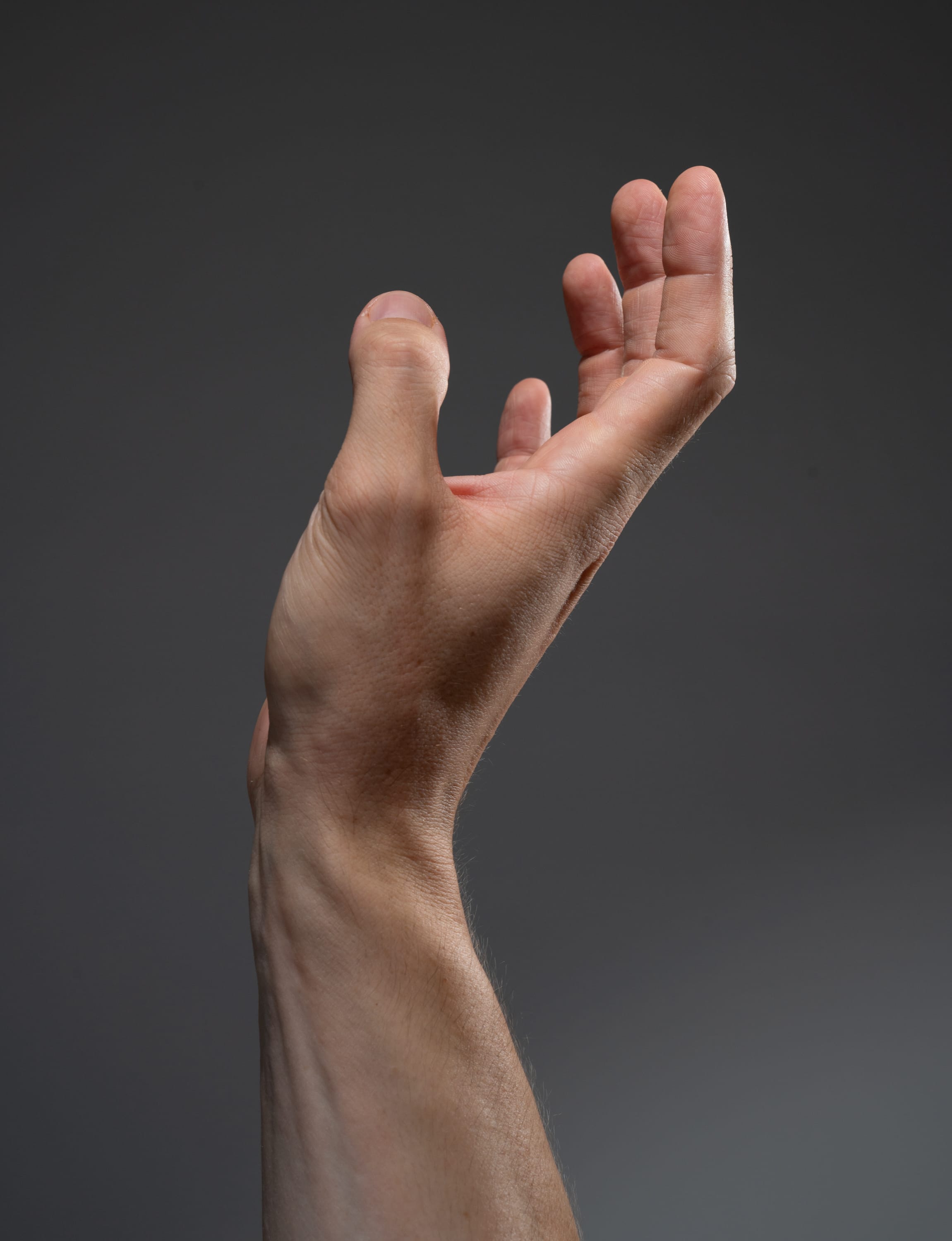 a man's right hand is extended against a gray background with the fingers slightly curled.