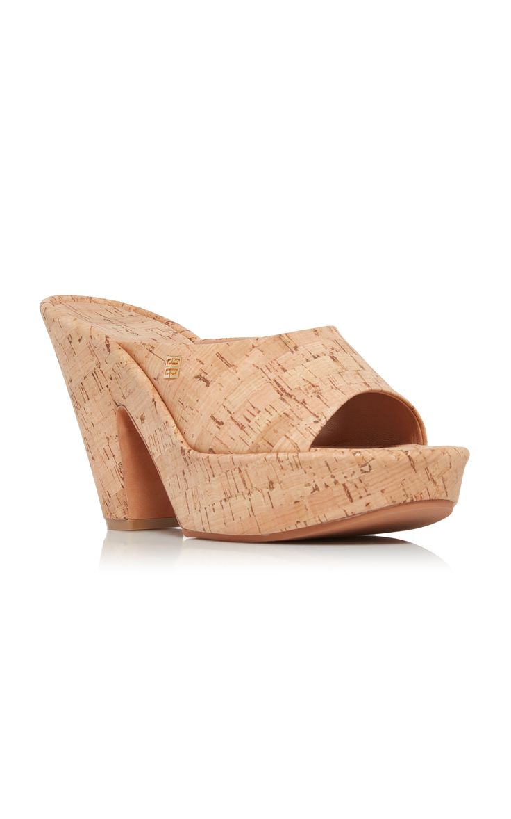 a pair of women's cork platform slide sandals are displayed on a white background. the sandals are light beige in color and have a chunky cork wedge heel. the upper is made of cork with a subtle pattern. the sandals have an open toe and a simple slide design.