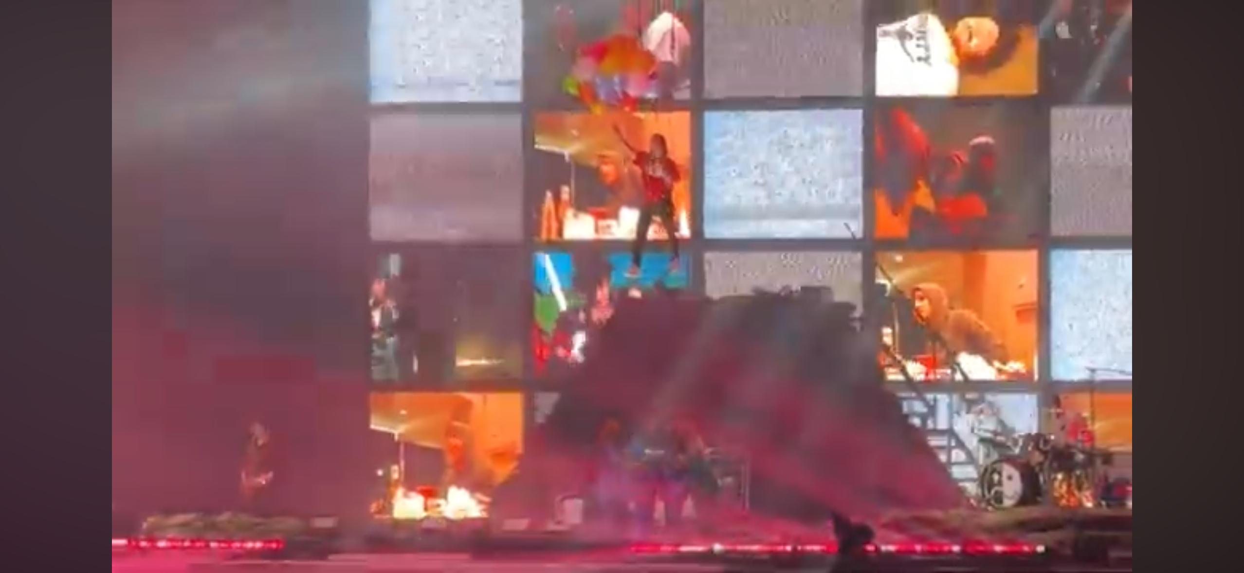 a live concert with a rock band performing on stage. the stage is set up with a drum kit, a microphone stand, and a guitar, and the band members are playing their instruments with passion. the crowd is enthusiastic and cheering, enjoying the energetic performance. the stage is lit up with bright lights, and the band members are illuminated in a colorful spotlight. the musicians look like they are having a great time, and the audience is feeding off of their energy.  the concert looks like it is an incredible experience for both the musicians and the fans.