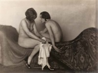 the black and white photograph depicts two nude women intimately positioned on a richly patterned, darkcolored fabric that drapes around them in a flowing, curvaceous manner.  the women appear to be in a soft embrace or close conversation, their bodies gently touching. the lighting is soft and diffused, emphasizing the textures of the skin and the fabric. the overall style evokes a sense of elegant sensuality and artistic beauty, suggestive of art photography from the early to mid20th century. the dark background contrasts sharply with the lighter tones of the women’s skin. the patterned fabric suggests a sense of opulence and adds depth to the composition.  the image holds a quiet, contemplative mood.