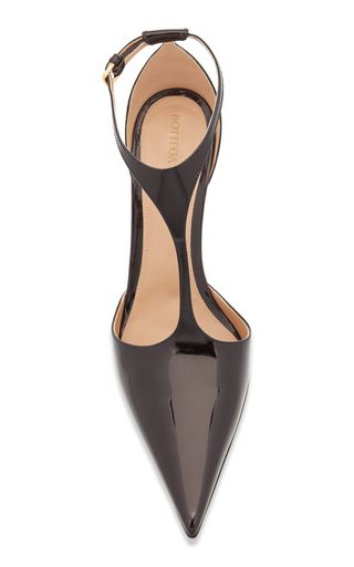 a closeup of a black patent leather highheeled shoe with a pointed toe and ankle strap.  the shoe has a stiletto heel and a sleek, elegant design. the brand name is visible on the insole.