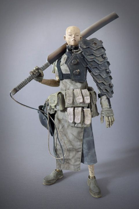 a closeup shot of a detailed action figure of a futuristic soldier. the figure is dressed in armor and a helmet, with a sword strapped to his back. he is standing with a serious expression on his face, ready for battle. the figure is made of plastic and is very detailed. the background is a plain gray wall.
