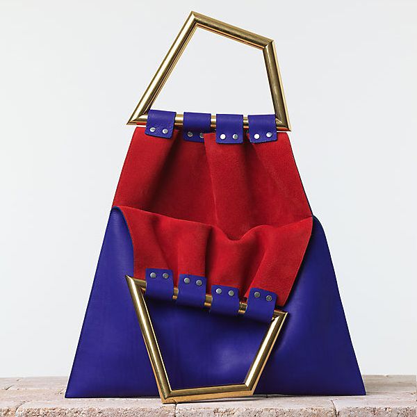 a blue leather handbag with a red suede interior. the bag has a gold metal frame and a triangular handle. it is a highend designer handbag.