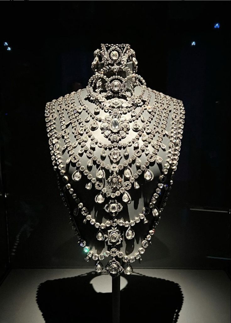 the image showcases a breathtaking, multilayered diamond necklace displayed on a mannequin against a dark background. the necklace is composed of numerous strands of diamonds of varying sizes and cuts, creating a cascading effect.  the piece appears to be quite elaborate and possibly antique or vintage, suggesting high value and craftsmanship. the dark background enhances the sparkle and brilliance of the diamonds. the overall impression is one of luxury and opulence. the photograph appears to be taken in a museum or exhibition setting, given the controlled lighting and display style.