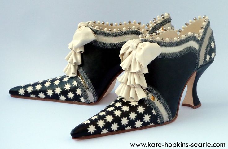 two black and white women's high heel shoes are shown on a white background. the shoes are elegant and unique. they are made with a black base and are adorned with a white star design. the shoes are made with a variety of materials, including leather, fabric, and metal. they are finished with a delicate ivory bow and a decorative silver beaded trim.