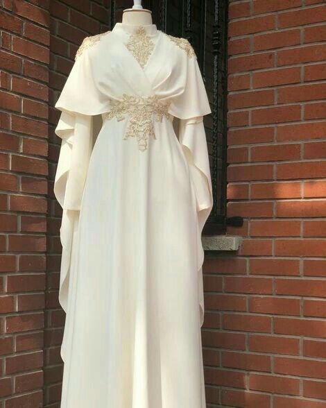 a white long dress with long sleeves and a delicate lace embroidery detail around the neckline and waist. the dress has a flowy skirt that falls to the floor. the dress is a formal or bridal dress and would be perfect for a special occasion. it looks like it's made from a fine, soft fabric and the detailing around the neckline and the sleeves adds a touch of elegance. it is a beautiful and elegant dress that would make any woman feel special.