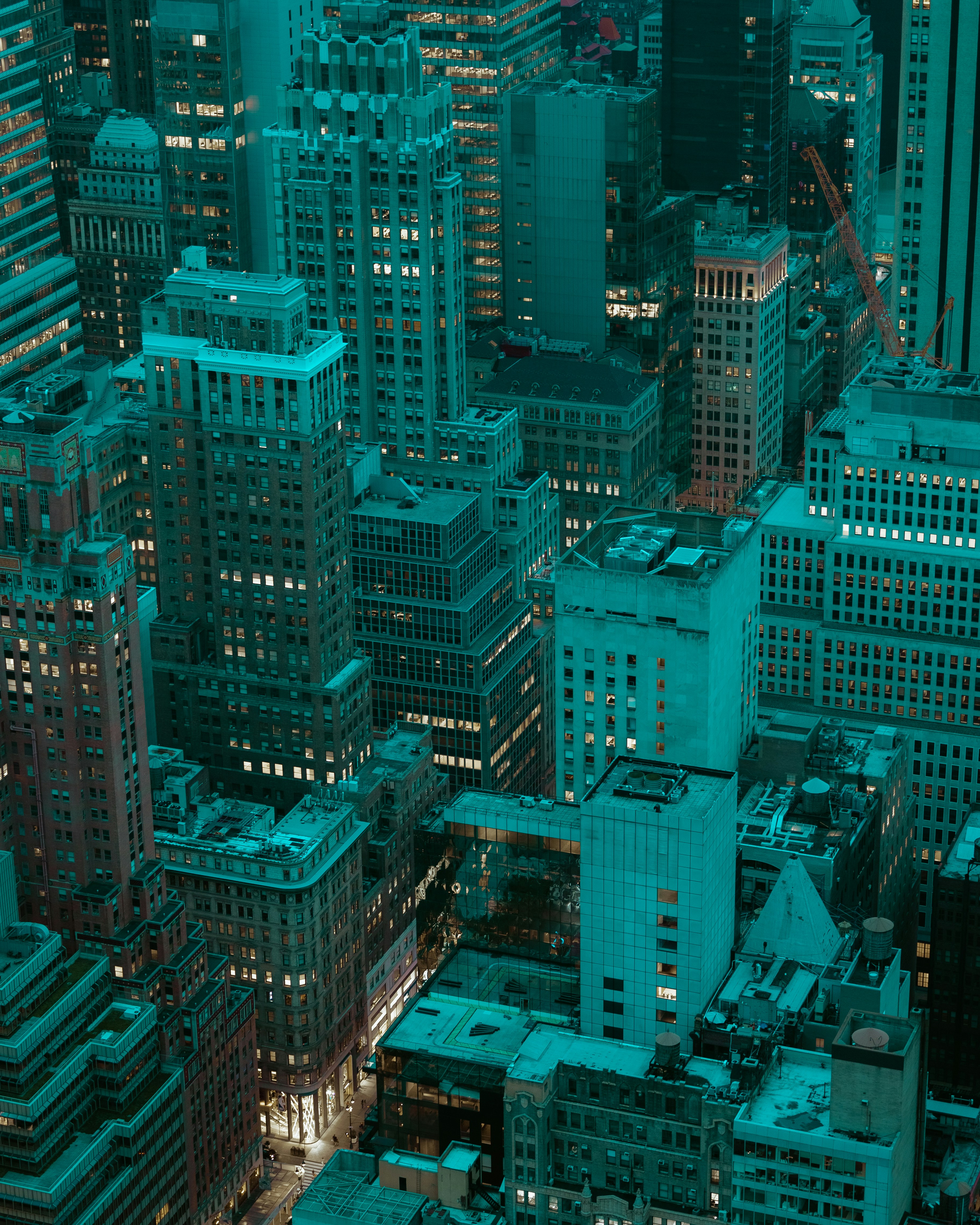 an aerial view of new york city at night, illuminated by the city lights. the image is dominated by skyscrapers and office buildings.