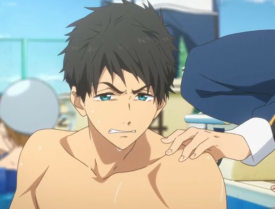 a closeup shot of a young man with dark hair and blue eyes standing by a swimming pool. he appears to be concerned or distressed, with furrowed brows and his mouth slightly open. his hair is wet, suggesting he was recently swimming. another person's hand is resting on his shoulder, as if offering comfort or support. the background is brightly lit, indicating a sunny day, and depicts a blurry swimming pool setting.