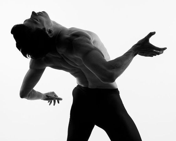 the image is a black and white photograph of a male dancer in midair, performing an expressive pose. his body is arched backward, with his arms outstretched and hands gracefully positioned. the highcontrast lighting emphasizes the muscular definition and fluid movements of the dancer. the studio setting provides a clean and minimalist backdrop, focusing attention solely on the dancer's artistry.