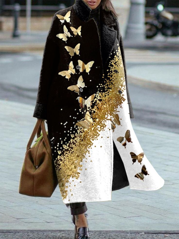 a woman is wearing a stylish black and white overcoat with gold butterfly and glitter detailing. she is holding a brown handbag and standing on a sidewalk. the coat features a unique design, with black on one side and white on the other, adorned with gold butterflies and glitter that appears to cascade down the front. she is wearing shiny black shoes. the scene appears to be an urban street setting, with blurred background elements such as a motorcycle and buildings.