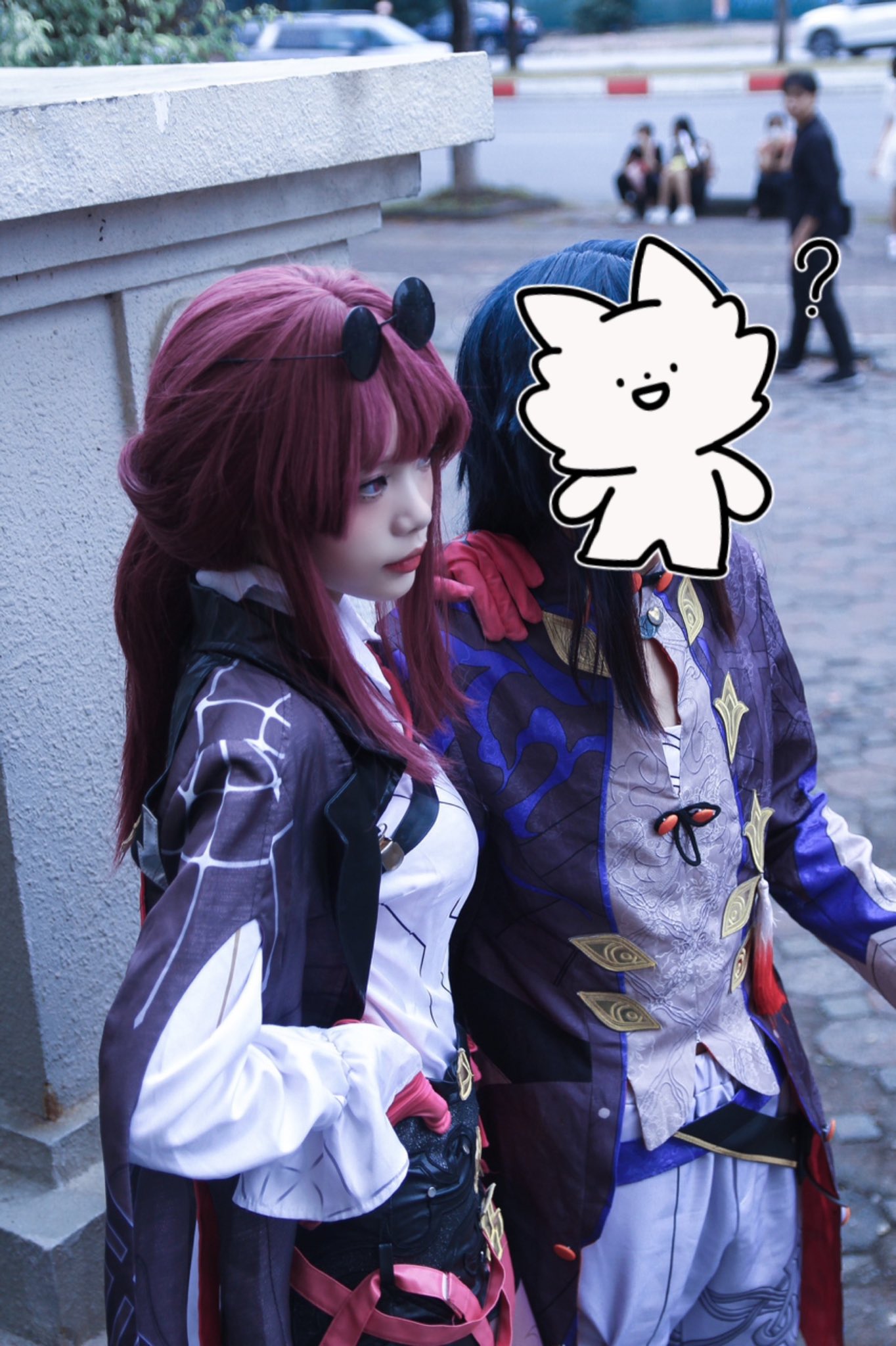 two people dressed up in anime cosplays. the girl is wearing a long purple coat with a white shirt underneath, and red gloves. the boy is wearing a long blue coat with a white shirt underneath, and a purple sash. they are both smiling and looking at the camera. the background is a city street.