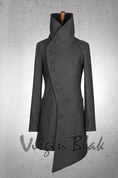 a long gray coat with a collar that stands up and a pointed hem. the coat has a row of buttons down the front and long sleeves. it is worn by a model who is standing against a gray background.