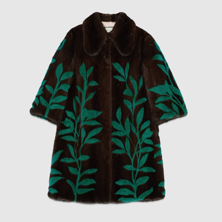 a brown fur coat with a dark brown collar and sleeves adorned with a green floral design featuring leaves. the coat is pictured against a light gray background.