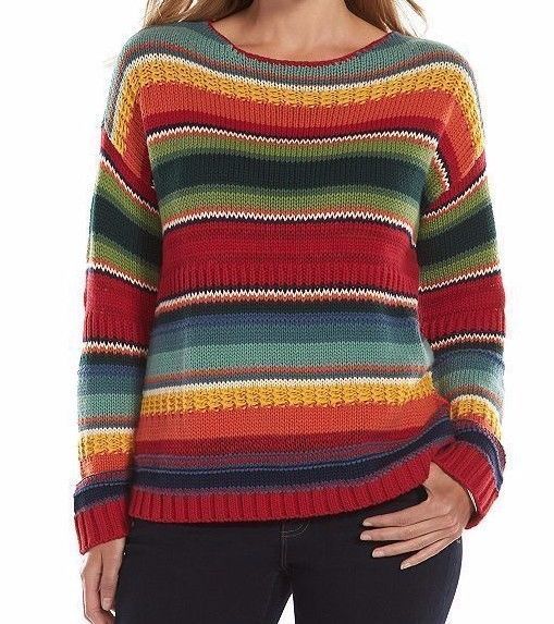 a woman is wearing a striped, colorful sweater with long sleeves. the sweater has a round neck and is made of knitwear. she is also wearing dark jeans. the overall style is casual and fashionable.