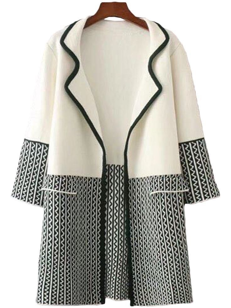 a white and black cardigan or coat on a hanger. the upper part is white with a black trim and the lower part has a black and white geometric pattern.