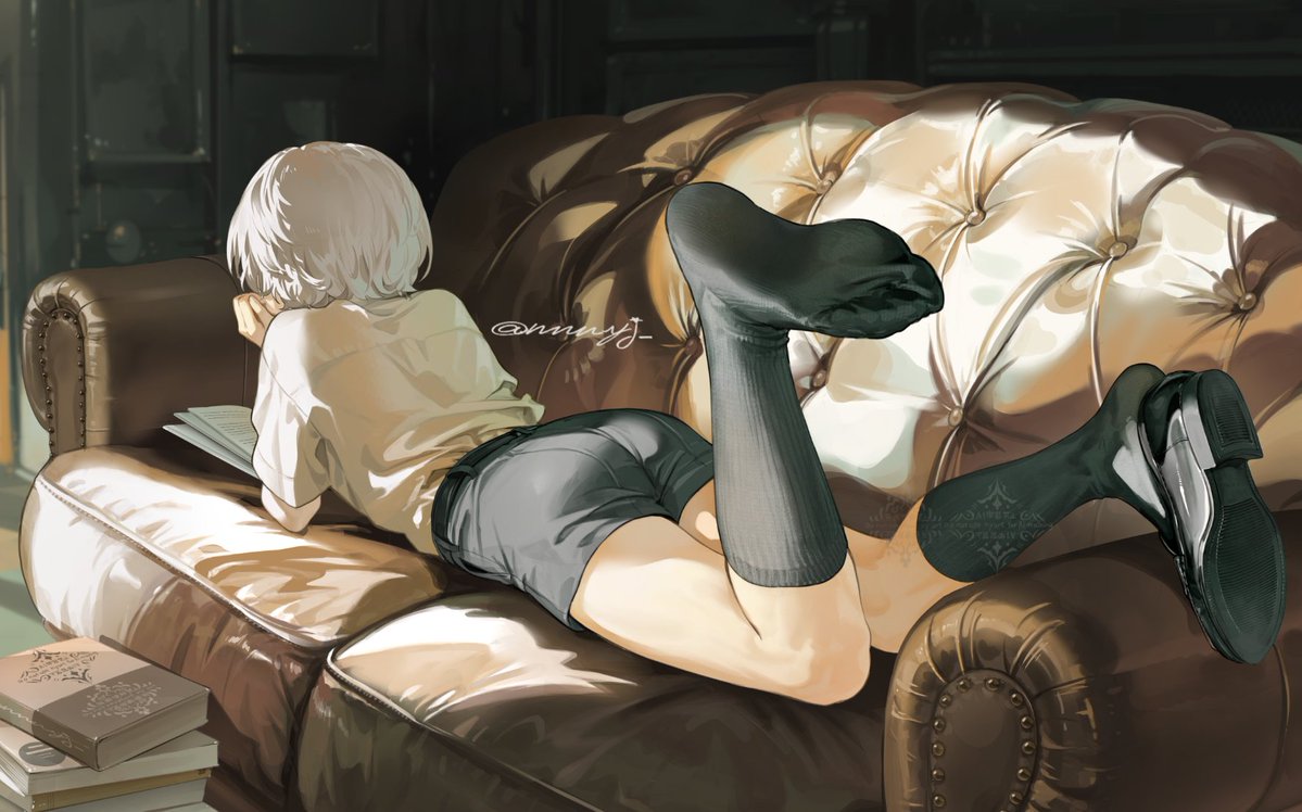 an animestyle illustration features a person with short white hair lying on a tufted leather couch, engrossed in a book. they are wearing a collared shirt, dark shorts, and black stockings. one leg is bent with a black shoe visible on the foot. a stack of books sits on the floor beside the couch. the background suggests a library setting.