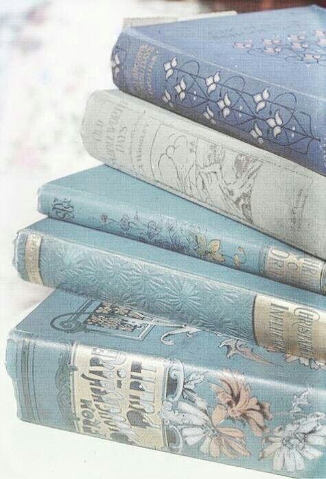 a stack of five vintage hardcover books in various shades of blue, featuring floral patterns and decorative covers.