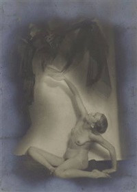 the image is a vintage, monochrome photograph of a nude female figure. the woman is posed in a dynamic, almost acrobatic position, her body arched and limbs extended. her form is partially obscured by shadows and a blurred, ethereal backdrop that resembles flowing fabric or drapery. the overall aesthetic is surreal and artistic, blending elements of classical nude photography with an abstract, dreamlike quality. the use of light and shadow creates depth and mystery, enhancing the emotional impact of the image. the photograph has a grainy texture indicative of its age and printing process, further contributing to its vintage character. the background appears to feature additional figures or shapes, although they are heavily obscured and unclear.  the overall impression is one of both beauty and enigma.
