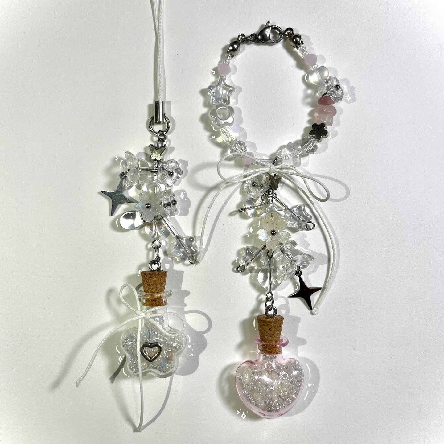 the image shows two handmade bottle charms. one charm has a heartshaped bottle filled with glitter and sealed with a cork, adorned with beads and flower accents. the other charm has a starshaped bottle filled with glitter and sealed with a cork, adorned with beads and flower accents.