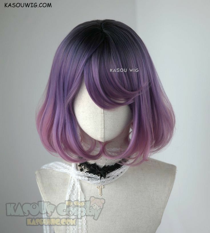 the image shows a mannequin wearing a short, ombre purple wig. the wig is styled into a bob with curled ends. the roots of the wig are black, fading into a dark purple and then a lighter purple with pinkishpurple tips. the mannequin is also wearing a white lace scarf with a black lace choker and a gold cross pendant. the backdrop is a plain light grey. there are logos on the wig and mannequin.