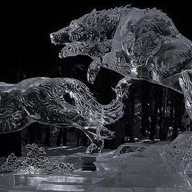 an image of an ice sculpture depicting two wolves in a dynamic pose, possibly fighting or interacting. the sculptures are finely detailed and set against a dark background.