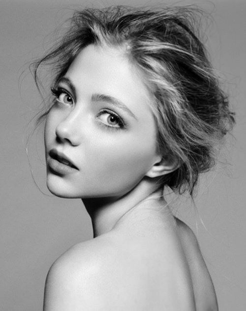 a black and white portrait of a beautiful young woman with a soft, natural look. her hair is styled in a simple updo, and her face is framed by wisps of hair. her eyes are soft and inviting, and her lips are slightly parted. her skin is flawless, and her expression is serene and confident. she is wearing no makeup, and her natural beauty shines through.