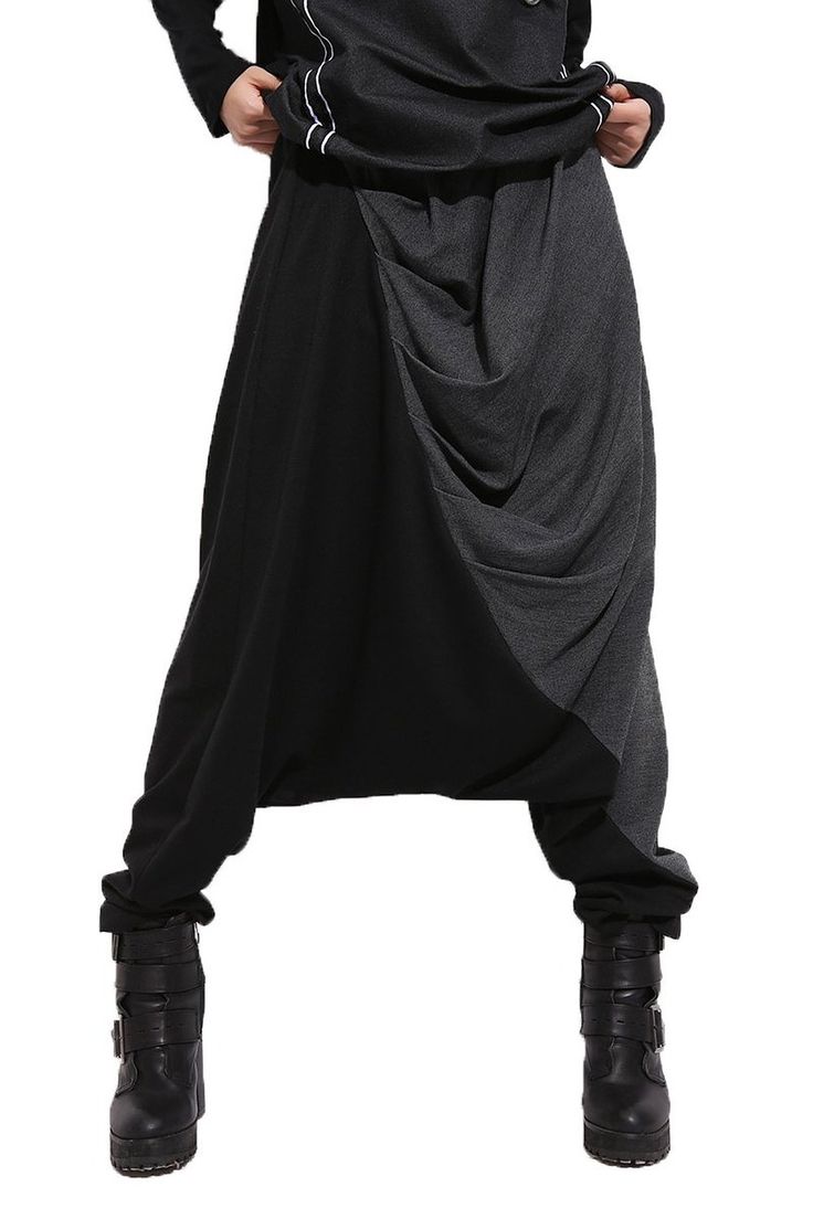 the image shows a person wearing black and gray draped pants with black boots. the pants are predominantly black, with a gray panel that drapes down the front. the person is wearing black boots that appear to be buckled. the background is plain white.