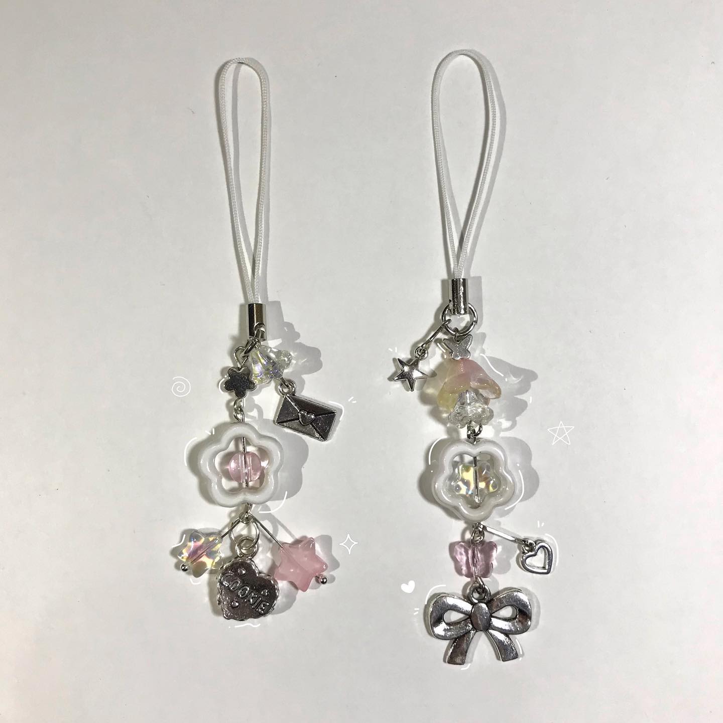 two beaded jewelry phone charms with different charms hang on a white background.