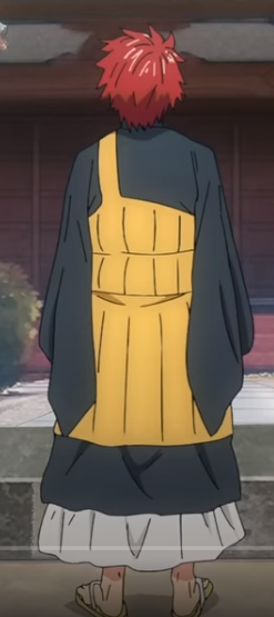 the image shows an anime character standing in front of a building. he is wearing a black robe with a yellow apron and a white skirt. he has red hair and is wearing shoes. the character is facing the viewer.