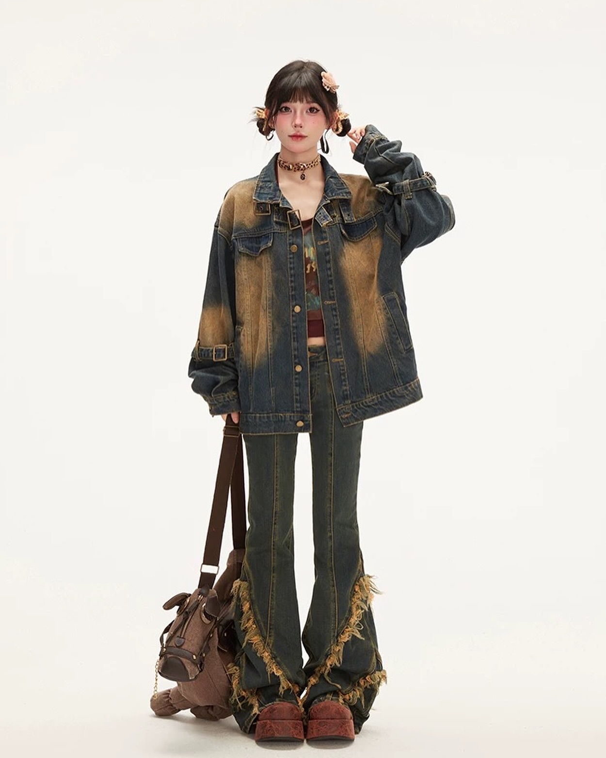 a young woman is standing in a studio shot against a white background. she is wearing a vintagestyle, distressed denim jacket with a faded and textured appearance and bell bottom jeans with frayed edges. the jeans are a dark wash with hints of brown fading. she also wears brown boots with maroon soles, a brown handbag slung across her body and a choker necklace. her dark hair is styled with loose bangs and two small clips on each side. the overall look is a casual, vintageinspired style.