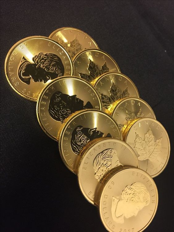 the image showcases a collection of gleaming gold coins, specifically canadian maple leaf coins. the coins are meticulously arranged, with their faces partially obscured, creating a visually appealing fanlike pattern. the coins' intricate details, including the profile of queen elizabeth ii and the iconic maple leaf design, are highlighted by the warm, artificial lighting.  this closeup perspective emphasizes the coins' texture, luster, and the artistry imprinted on their surfaces. the overall impression is one of affluence, prosperity, and the allure of precious metals.