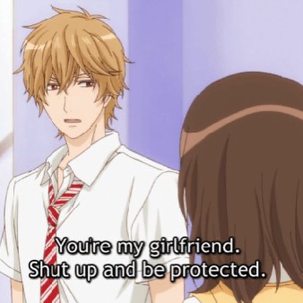 the image shows a scene from an anime or manga. a young man with messy, light brown hair and red eyes is speaking to a young woman. he is wearing a white shirt, red and white striped tie, and a white jacket. the woman has long, dark brown hair and is facing away from the viewer. the background is a plain, light purple wall, suggesting a school hallway setting. the man's expression is serious, and his words, "you're my girlfriend. shut up and be protected," suggest a possessive and protective personality.