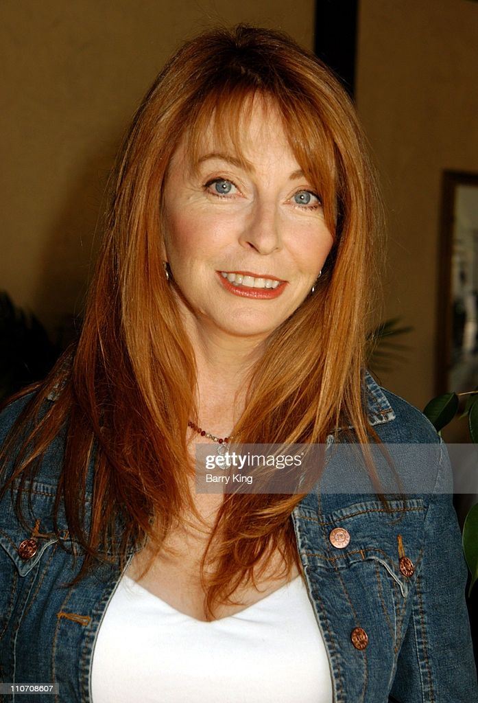 a closeup portrait of a beautiful redheaded woman wearing a denim jacket and a white shirt, smiling brightly at the camera. her hair is long and flowing, and she has a warm and friendly expression. her skin is lightly wrinkled, adding to her natural charm. she is looking directly at the viewer, with a sense of confidence and selfassurance.