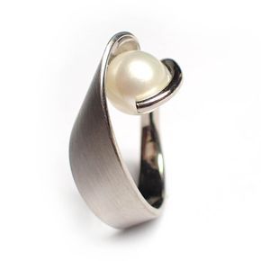 a closeup shot of a white gold ring with a single, round pearl set in a simple, modern design. the ring is made of brushed white gold and the pearl is set in a smooth, rounded setting. the ring is elegant and simple, with a minimalist aesthetic.