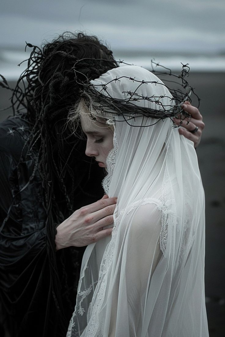 a woman in a white veil with a crown of thorns is embraced by a man in black. the woman is looking down, her face is obscured by the veil. the man's hand is resting on her shoulder. the background is a dark and misty beach.  the image is dark and moody, with a sense of mystery and romance.  the composition is simple, with the couple in the center of the frame. the contrast between the white of the woman's veil and the black of the man's clothing is striking. the image evokes a sense of love, loss, and sacrifice. the overall effect is dreamy and ethereal, with a touch of melancholy.