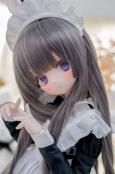 a doll with grey hair and purple eyes is dressed in a maid outfit with a white dress and black trim. she has a soft, innocent expression and is posed with her hands gently clasped in front of her.